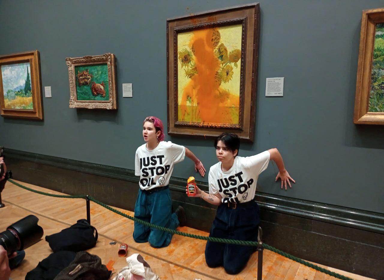 "Just Stop Oil" activists kneel on the floor with their hands glued to the wall after throwing soup at Vincent van Gogh's "Sunflowers" painting at the National Gallery in London, United Kingdom, on October 14, 2022.