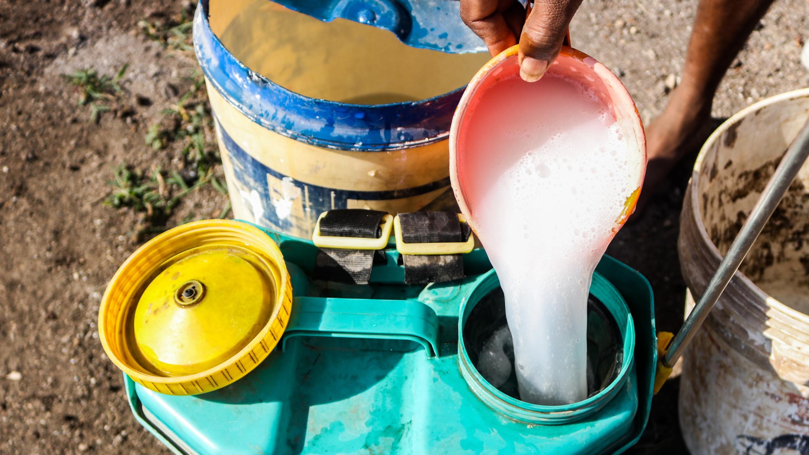 A farmer preparing a mixture of potent chemical pesticides to protect his vegetables.Â